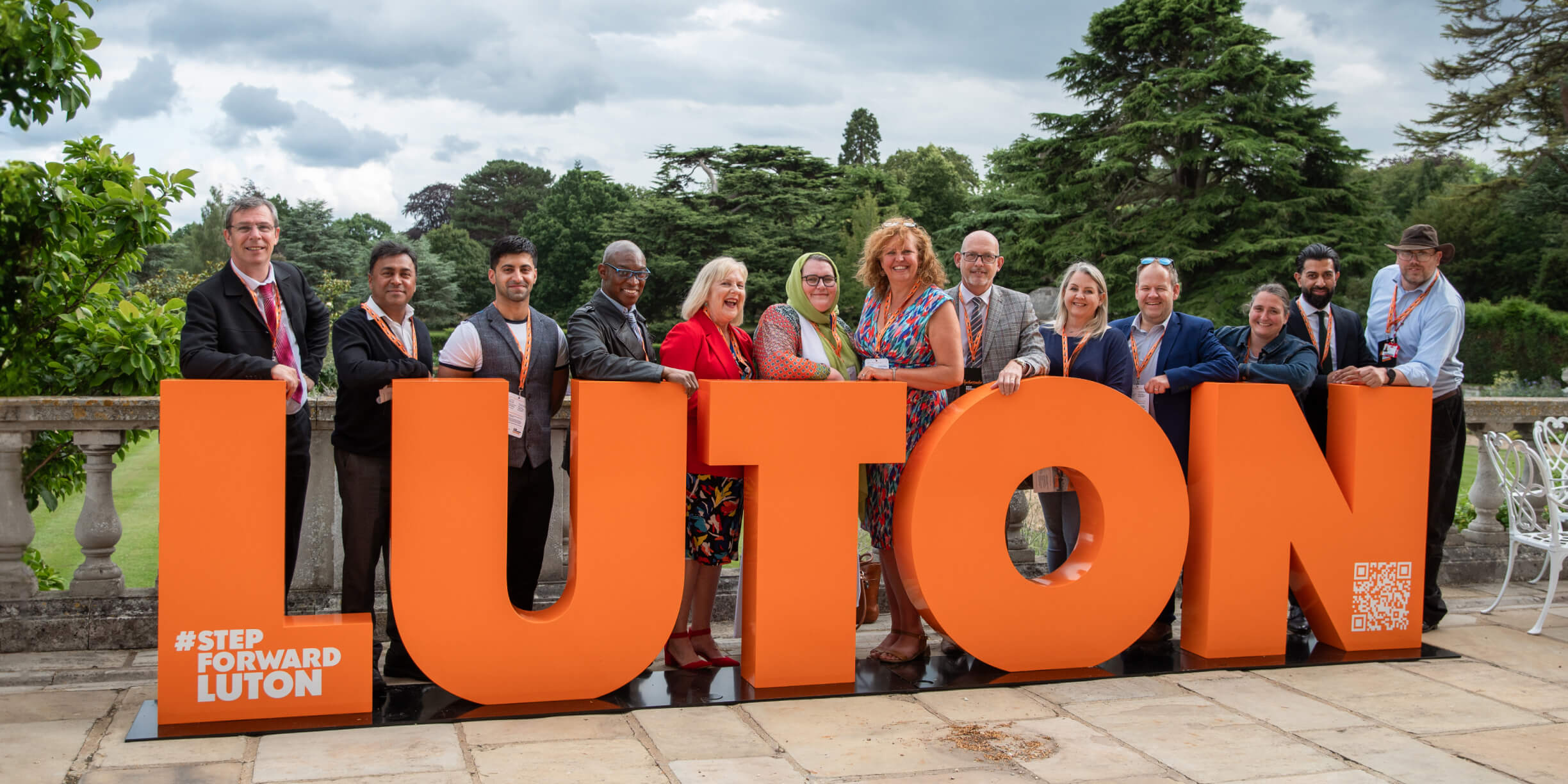 Luton's ambassadors gather around bright orange 3d letters spelling Luton